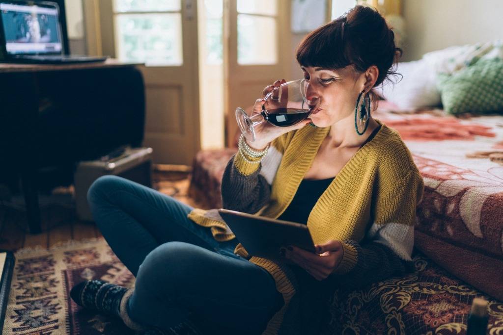 woman drinking wine and reading an e-book